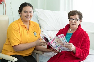 Volunteer pictured with patient, reading a magazine together
